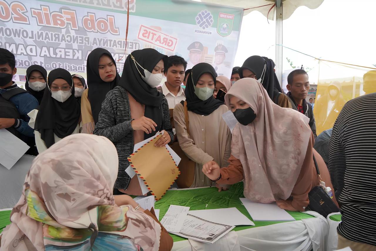 PENGANGGURAN: Pencari kerja menyerahkan berkas lamaran kepada perusahaan saat job fair di Kabupaten Tanah Bumbu. Warga lokal bersaing dengan migrasi pekerja untuk mendapatkan pekerjaan.