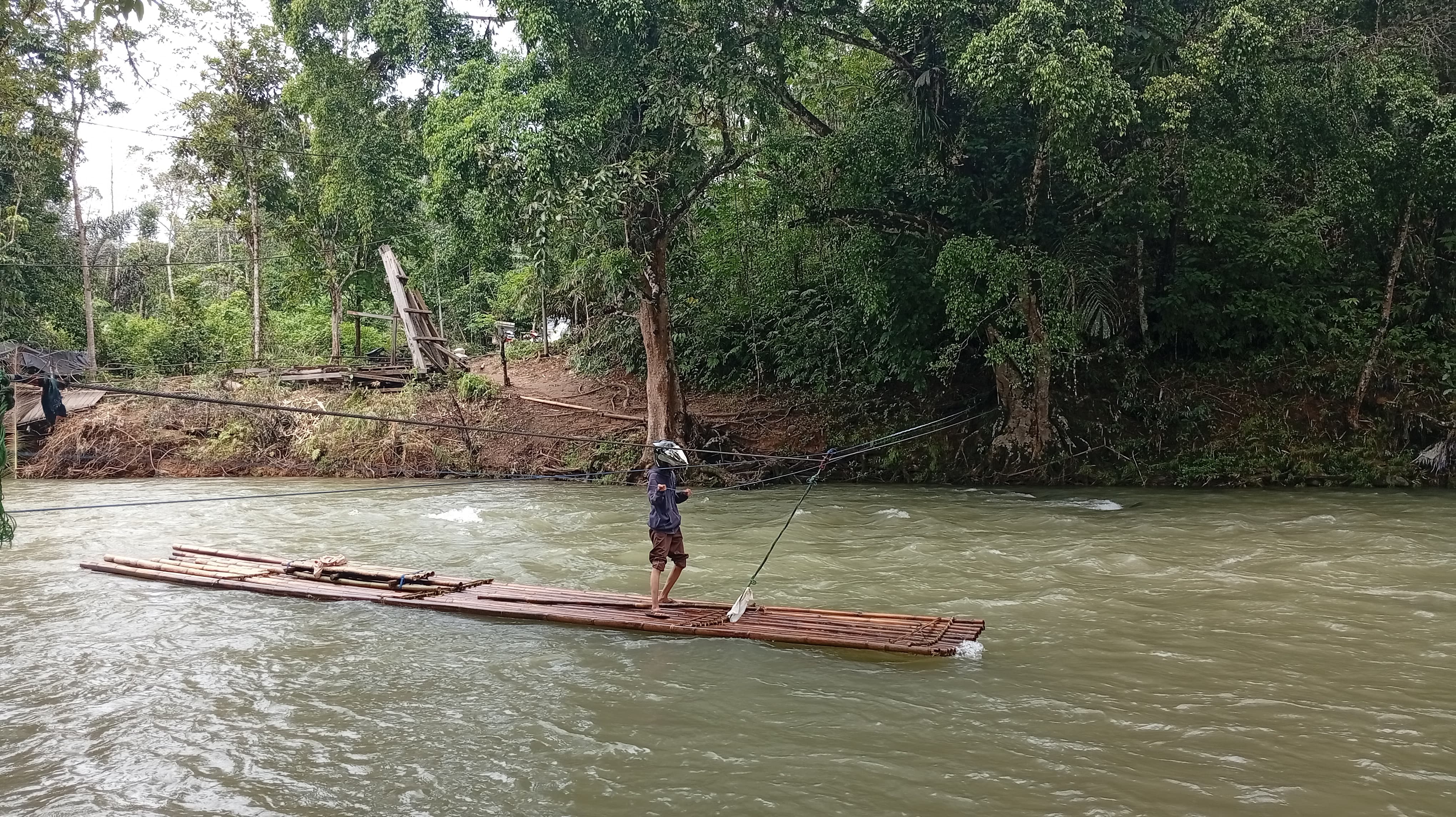 RAKIT: Salah satu warga saat menyeberangi sungai menggunakan rakit bambu. (Foto: M. Padil Ihsan/Radar Banjarmasin)