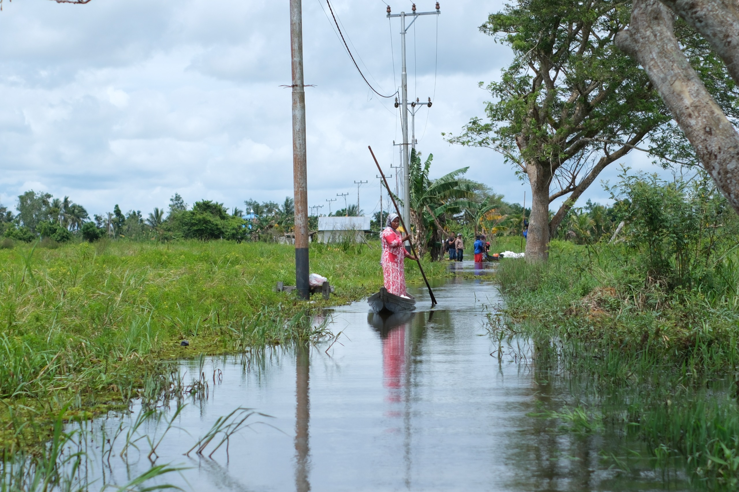 PAKAI JUKUNG: Warga melewati jalan di Desa Kayu Rabah yang masih terendam banjir. Bupati HST Samsul Rizal berjanji akan tinggikan jalan di desa ini.
