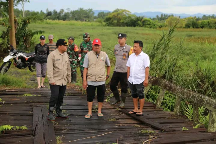 PERBAIKAN: Wakil Bupati HSS, H. Suriani, saat meninjau langsung kerusakan jembatan kayu di Desa Panjampang Bahagia yang hancur akibat diterjang banjir.