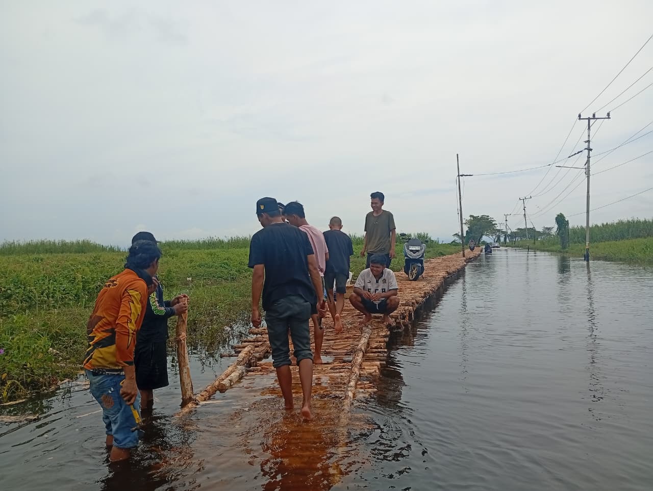 GOTONG ROYONG: Warga Desa Bangkau membangun jembatan darurat untuk membantu motor melewati akses Kandangan-Nagara yang terendam banjir berminggu-minggu.