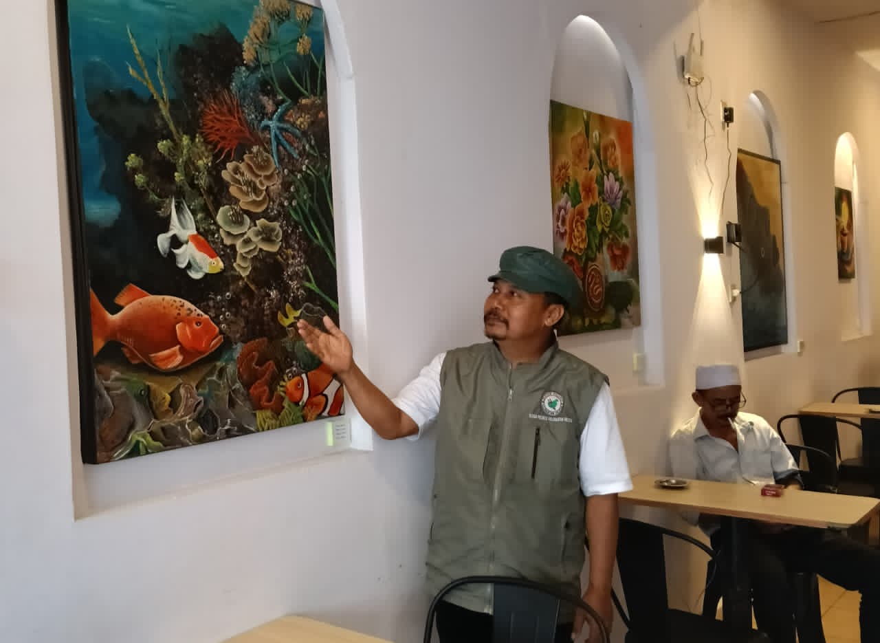 KOLABORASI SENI:Kris Imanu bersama salah satu lukisan yang dipamerkan di Cafe Tradisi.