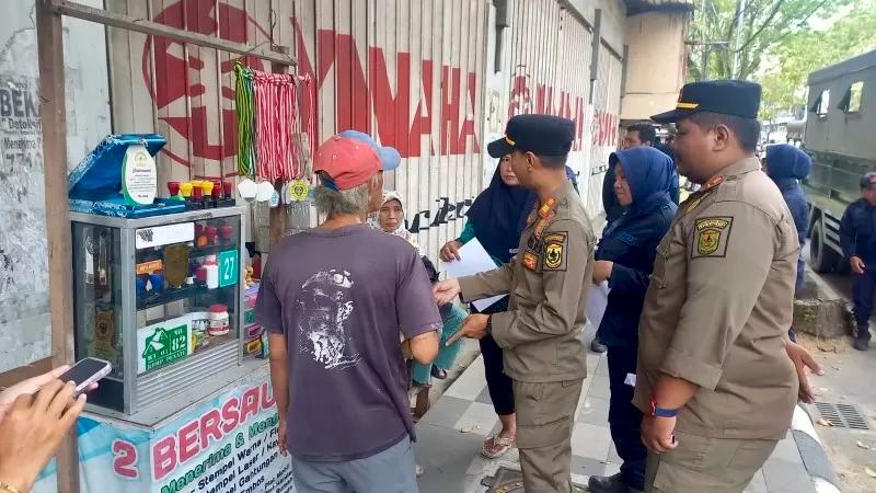 DILANJUTKAN 2026: Petugas Satpol PP Kota Banjarmasin bersama Dishub melakukan penertiban PKL yang berjualan di atas trotoar kawasan jalur protokol.