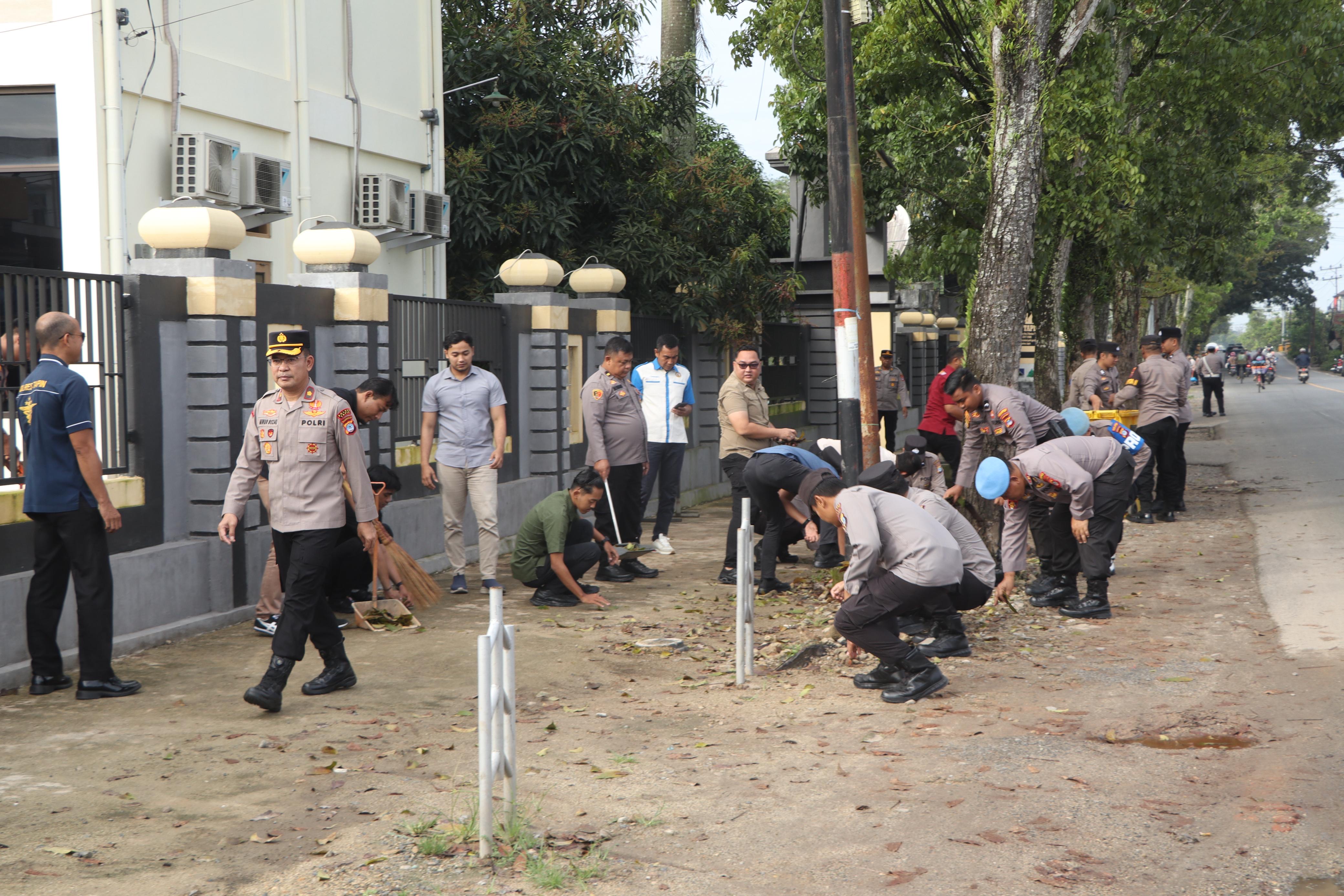 Anggota Polres Tapin memungut sampah yang ada di jalan A Yani Kelurahan Bitahan Kecamatan Lokpaikat.