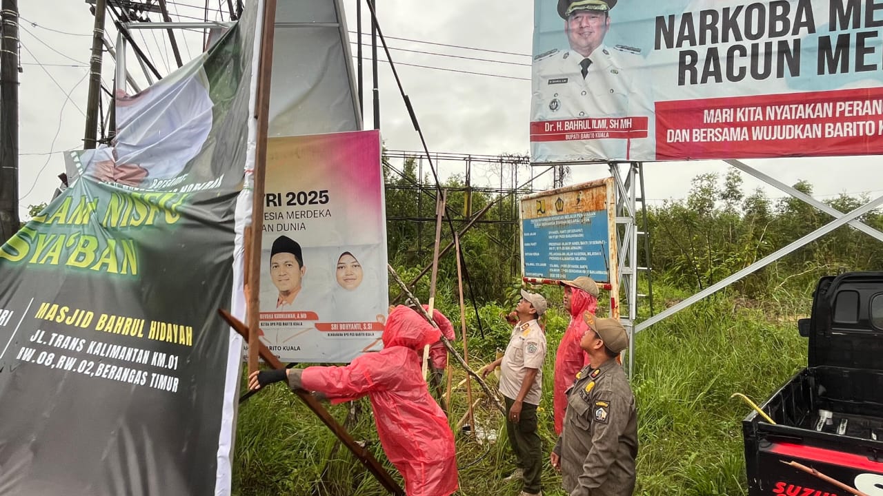 DITERTIBKAN: Petugas Satpol PP Barito Kuala saat menurunkan spanduk dan baliho di sepanjang jalan poros wilayah Alalak, tepatnya di perempatan Handil Bakti.