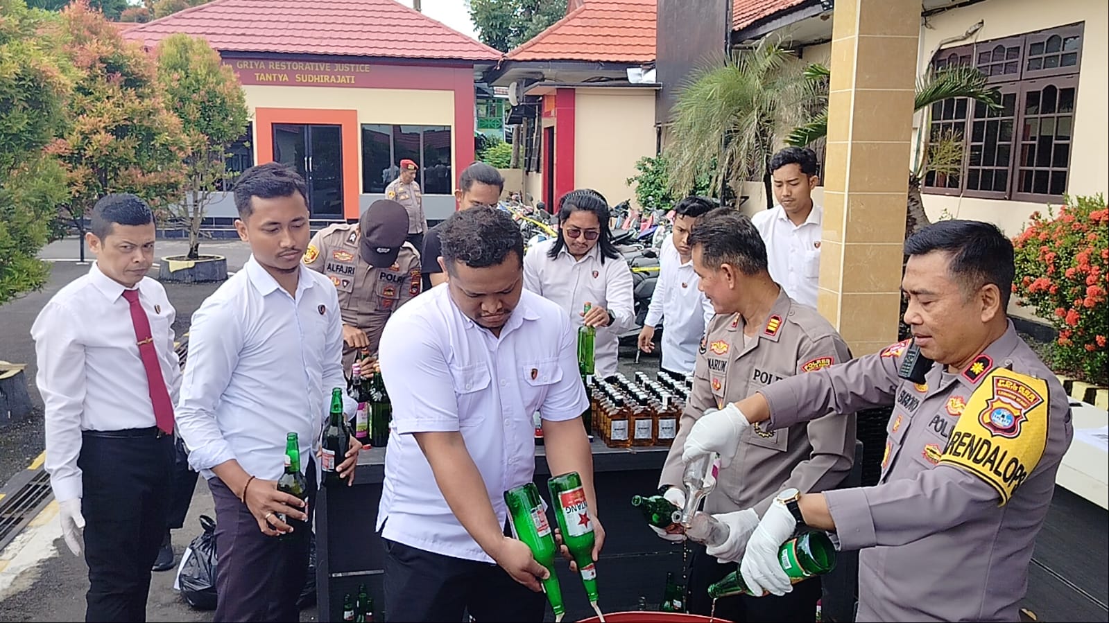DIMUSNAHKAN: Satu per satu botol berisi minuman keras dituangkan ke dalam drum plastik bercampur deterjen saat pemusnahan di Mapolres Batola.