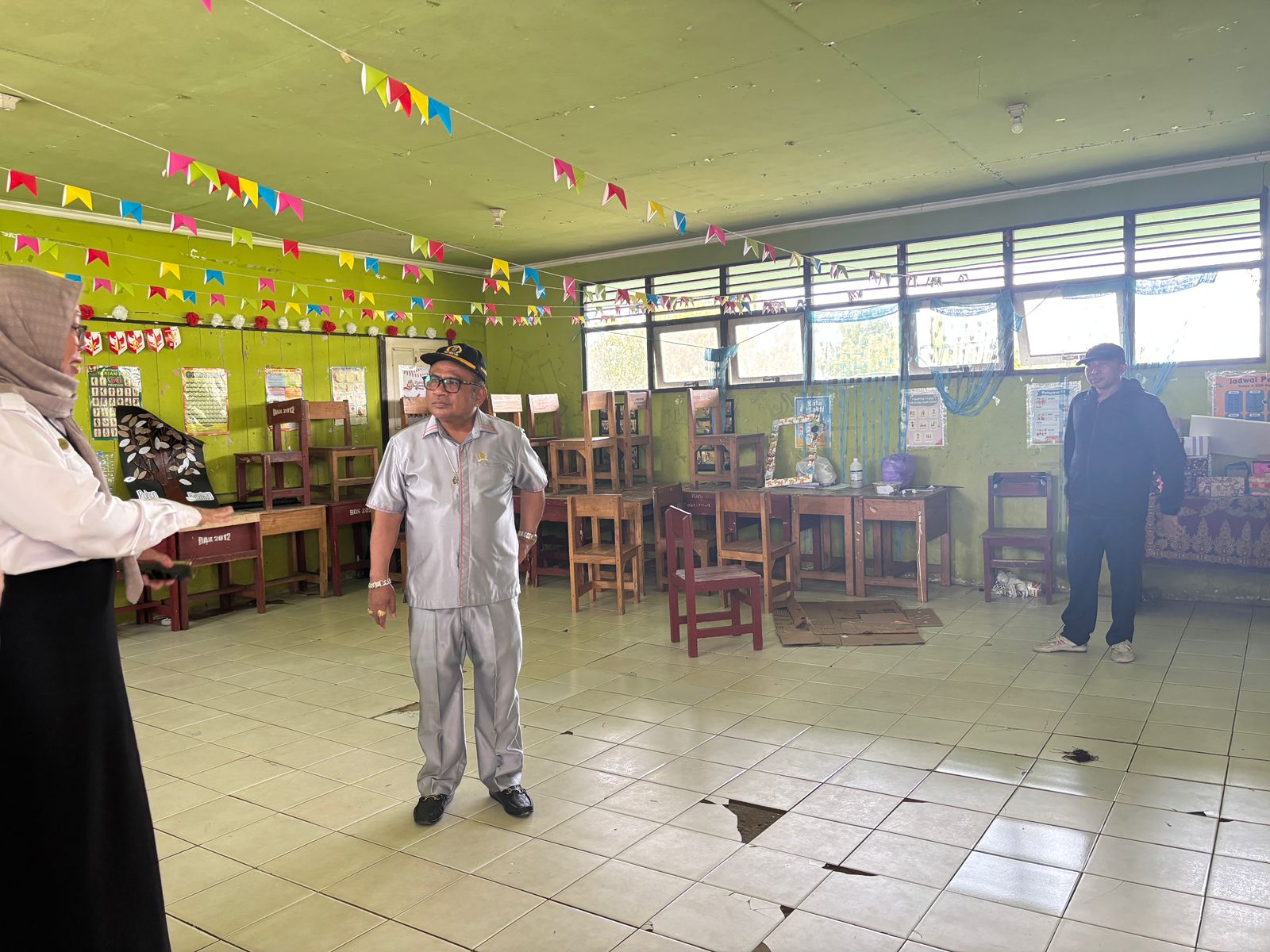 Anggota Komisi IV DPRD Banjarmasin, Saut Nathan Samosir meninjau kondisi lantai kelas yang melengkung di SDN Sungai Lulut 3 Banjarmasin. (Saut Nathan untuk Radar Banjarmasin)