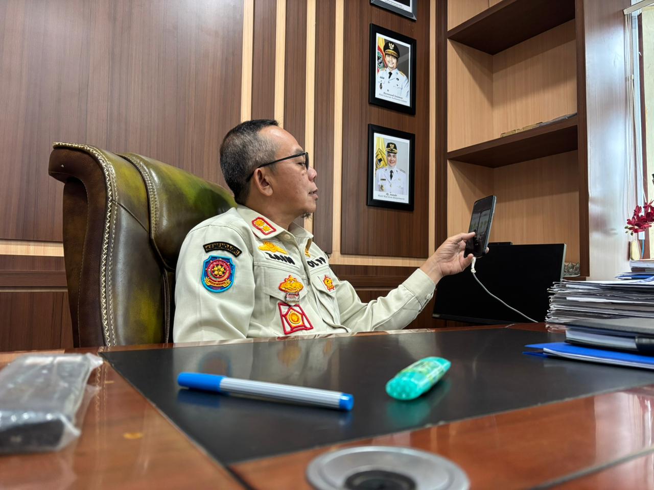 TENGOK HANDPHONE: Kepala Satpol PP Banjarmasin Ahmad Muzaiyin menunjukkan sejumlah dokumentasi hasil penegakkan Perda Ramadan.
