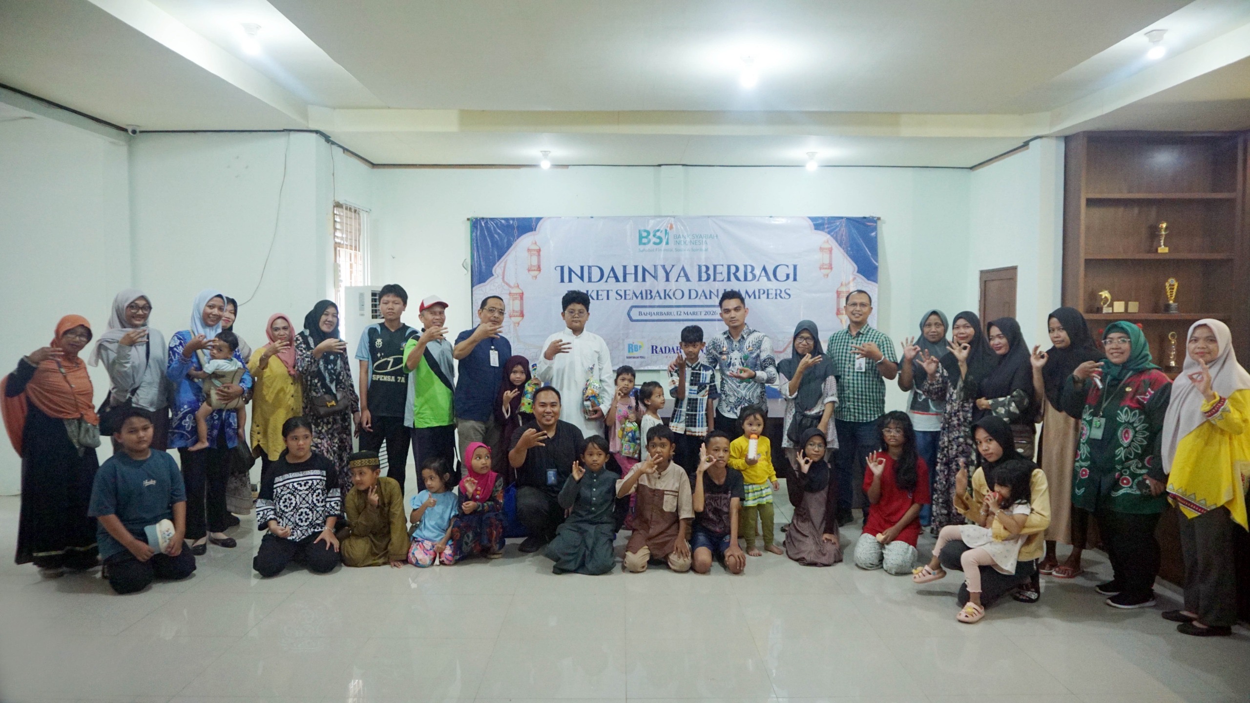 KEBERSAMAAN: Perwakilan BSI, aparat kelurahan, serta para penerima bantuan berfoto bersama usai penyaluran paket sembako dan hampers bagi duafa dan anak yatim di Kelurahan Guntung Paikat.