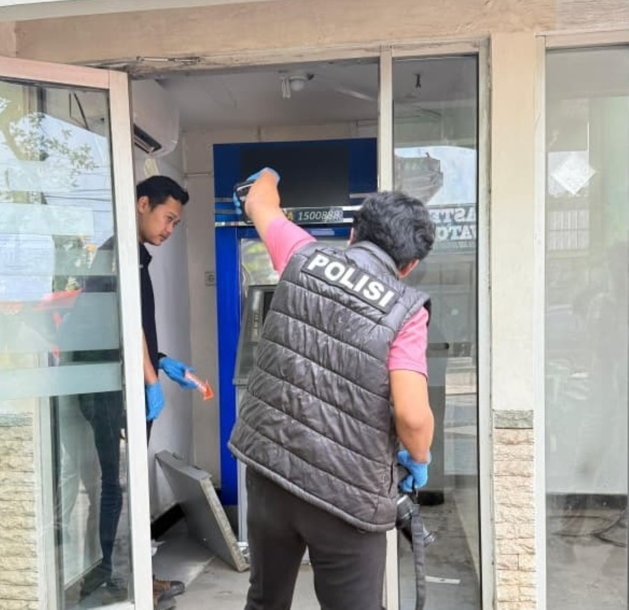PEMBOBOLAN: Petugas kepolisian memasang garis polisi di mesin ATM BCA di Jalan Ahmad Yani Km 39, Martapura, yang menjadi lokasi dugaan percobaan pembobolan, Kamis (12/3/2026). (POLRES BANJAR)
