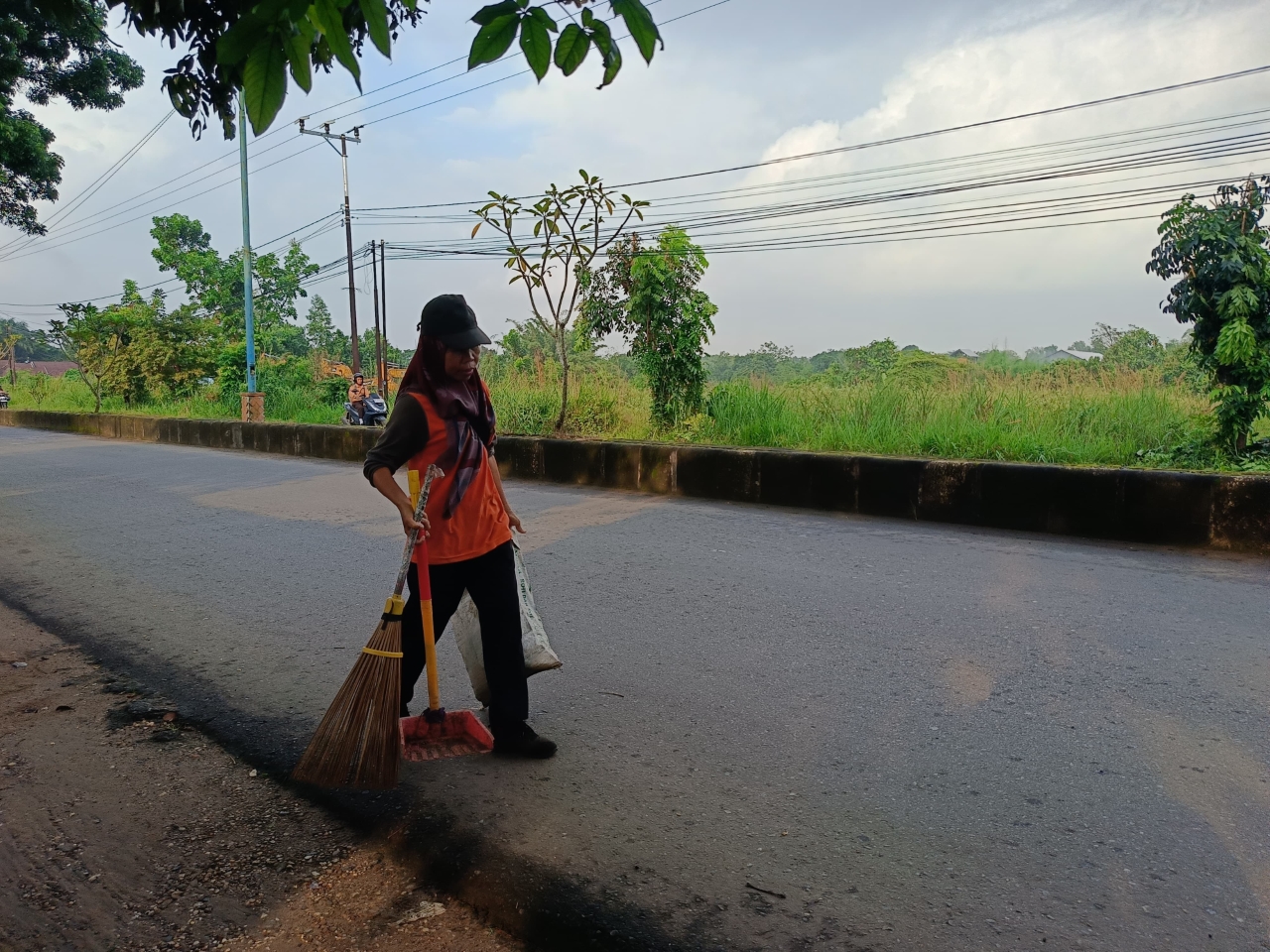 MEMBERSIHKAN: Parida saat membersihkan sampah di Jalan Guntung Manggis, Kelurahan Guntung Manggis, Kecamatan Landasan Ulin. 