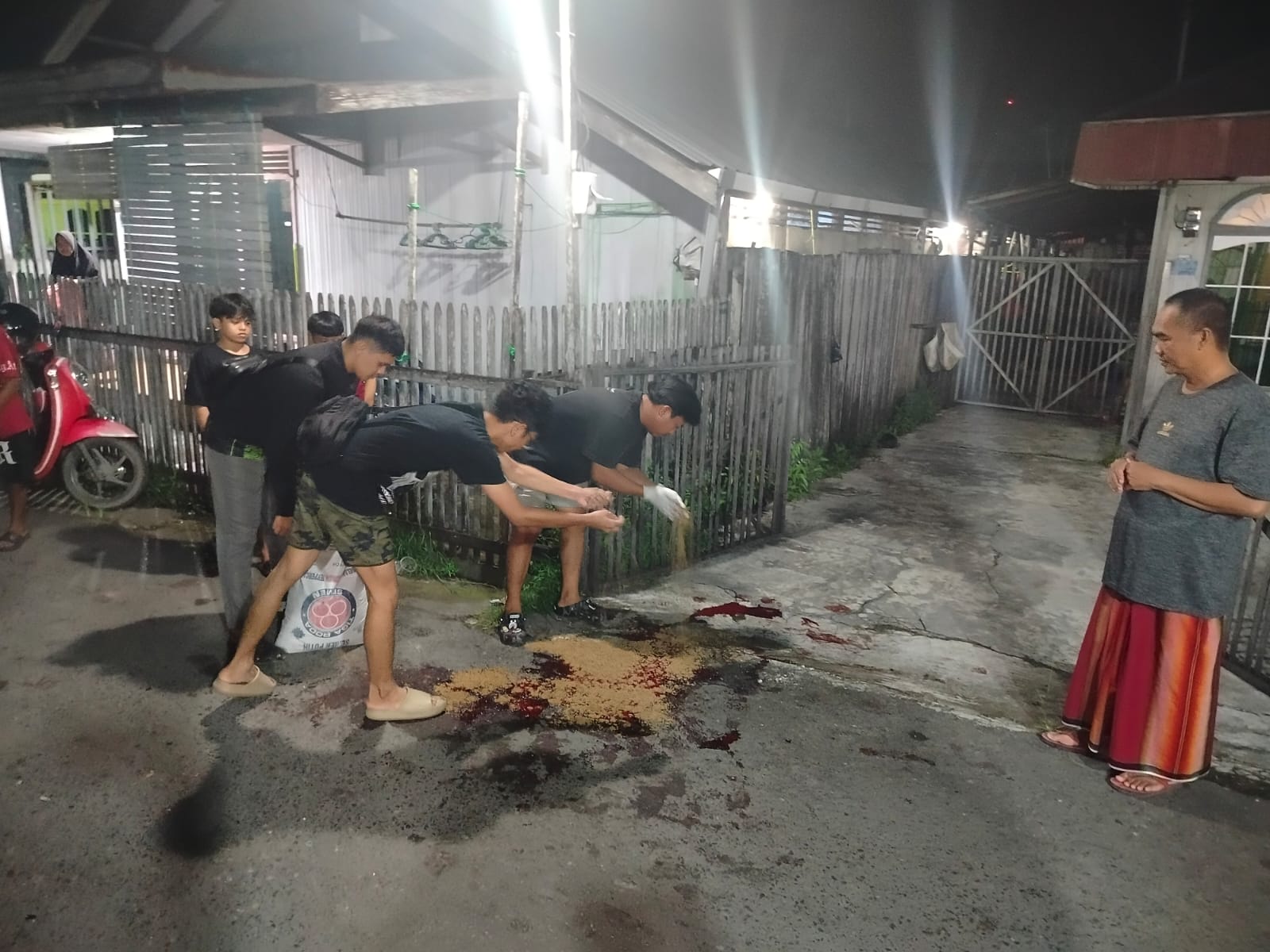KASUS PENGEROYOKAN: Warga dan relawan Damkar Pekapuran Raya membersihkan bekas darah korban di lokasi kejadian, Senin (16/3/2026) malam.  