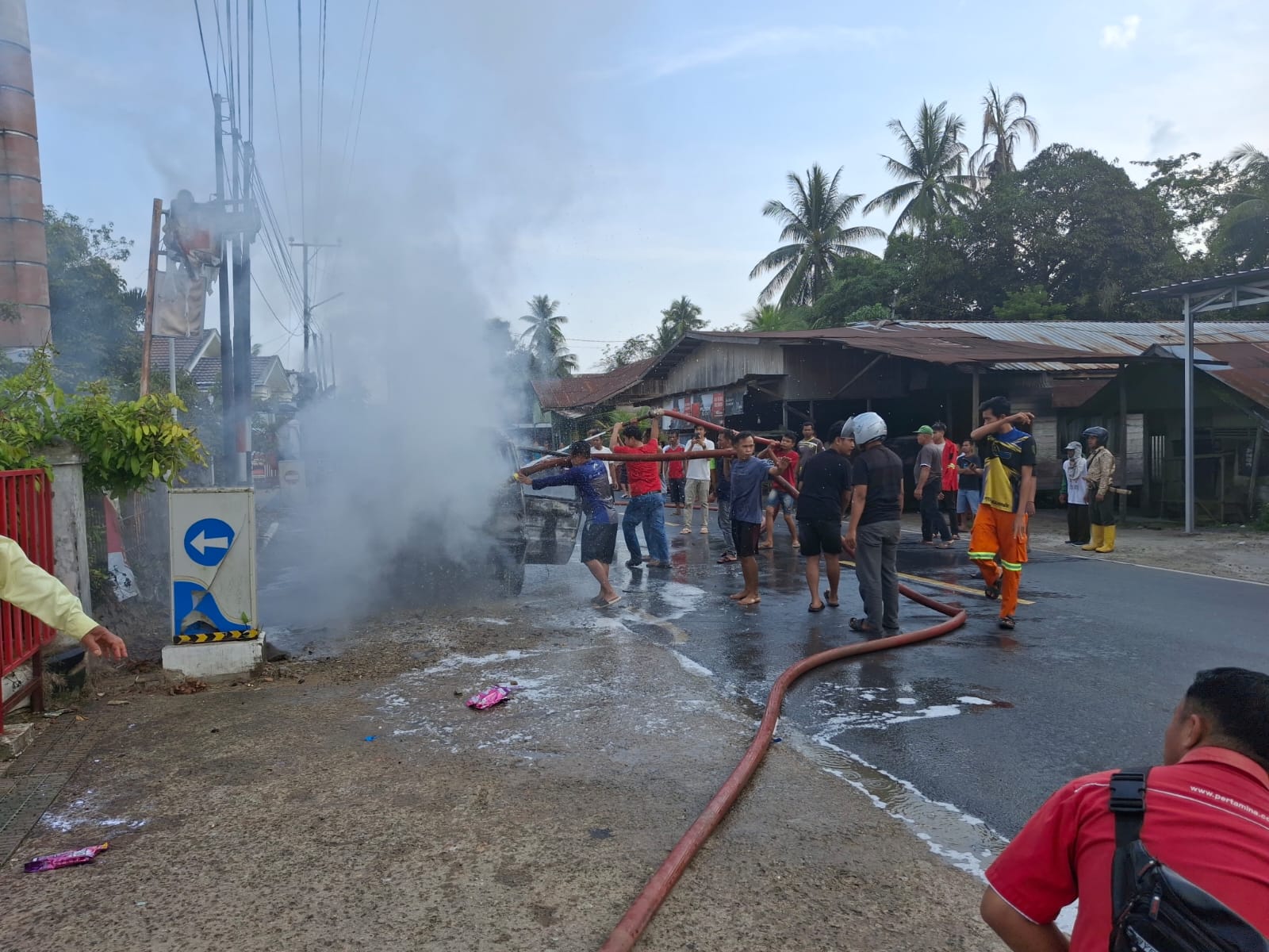 TERBAKAR : Mobil milik HAR yang terbakar dipadamkan warga dan petugas pemadam.  (Foto : Polres Tabalong untuk Radar Banjarmasin)