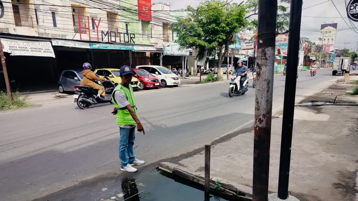 MENGGENANG: Juru parkir menunjukkan salah satu lubang got yang menggenang di kawasan Sultan Adam, Banjarmasin.