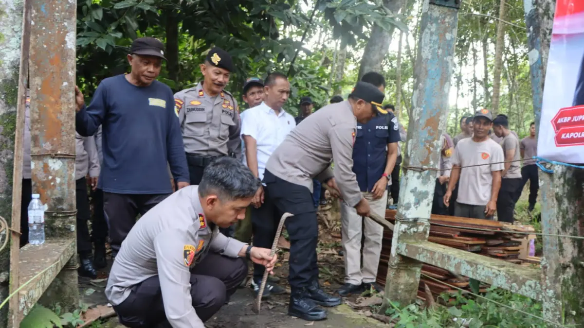 TERJUN LANGSUNG: Kapolres HST, AKBP Jupri JHP Tampubolon (duduk) pimpin gotong royong perbaikan jembatan di Murung Taal. (Foto: Jamaluddin/Radar Banjarmasin)