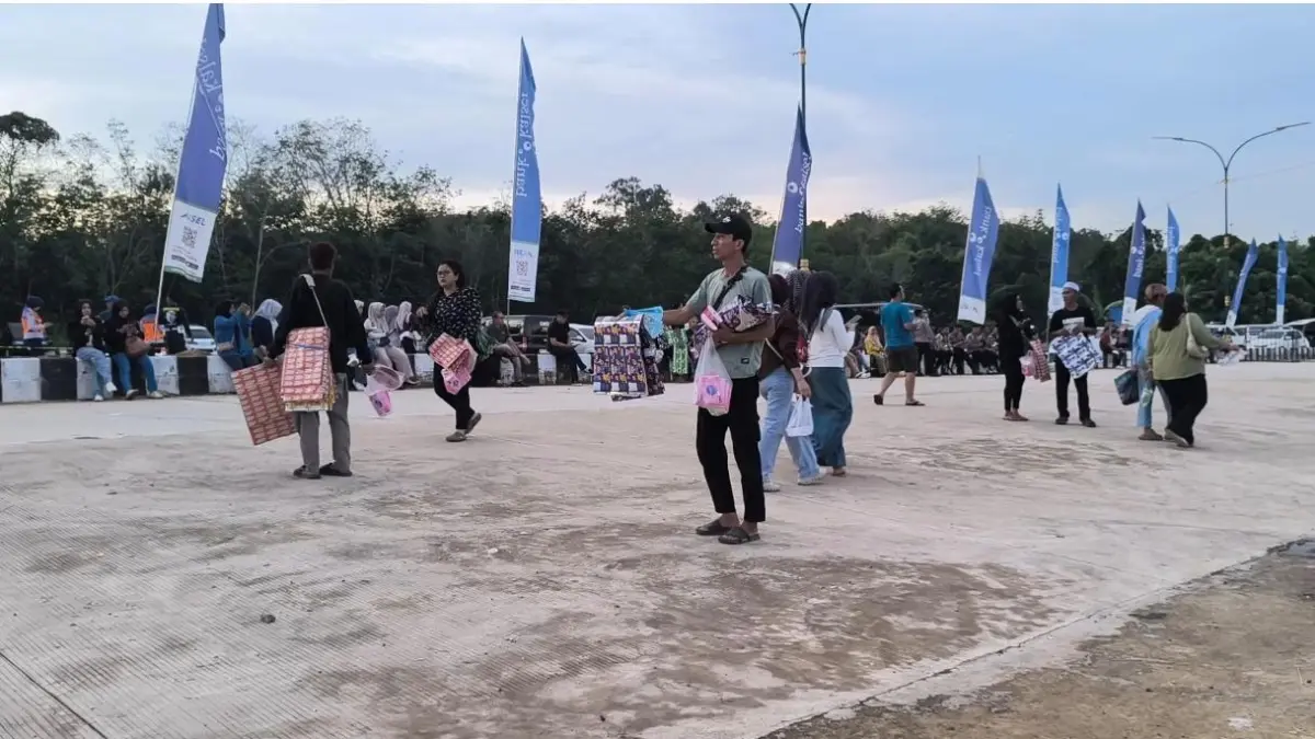 ALAS DUDUK: Penjual alas duduk saat menawarkan dagangannya kepada penonton konser Dewa 19 di kawasan Tugu Maritam, Paringin. (Foto: M Dirga/Radar Banjarmasin)