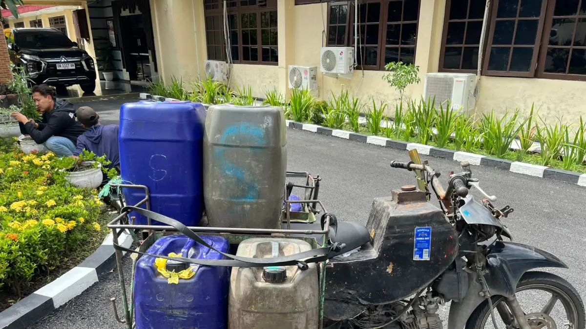 BARANG BUKTI: Petugas menunjukkan jeriken berisi BBM bersubsidi dan motor bertangki modifikasi milik pelaku saat diamankan di Mapolres HSU, Kamis (16/4/2026).
