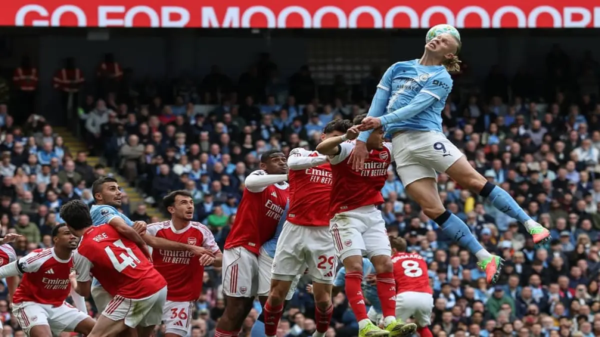 MENJAGA: Para pemain Arsenal menjaga penyerang Manchester City Erling Haaland yang menyundul bola di pertandingan Liga Primer Inggris, Minggu (19/4).&nbsp;
(AFP/Darren Staples)