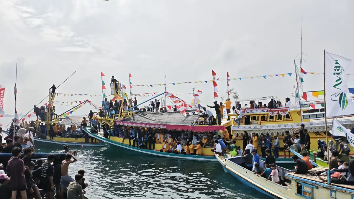 PROSESI: Sandro saat hendak melarung sesajen ke laut dalam puncak Mappanre Ri Tasi’e di perairan Pagatan, Tanah Bumbu, Ahad (26/4). (Foto: Zulqarnain/Radar Banjarmasin)