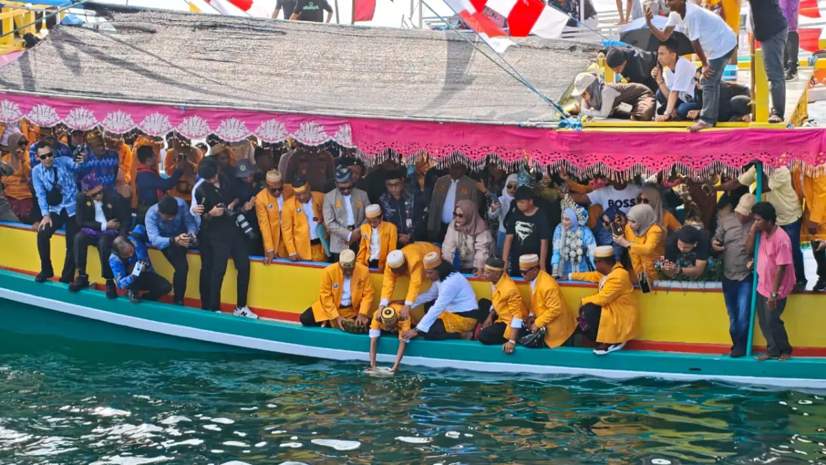 PROSESI: Sandro saat hendak melarung sesajen ke laut dalam puncak Mappanre Ri Tasi’e di perairan Pagatan, Tanah Bumbu, Ahad (26/4). (Foto: Zulqarnain/Radar Banjarmasin)
