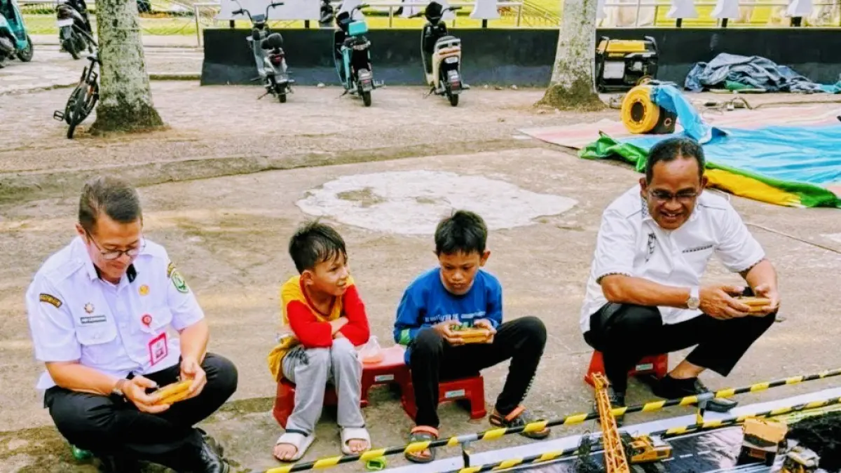 Bupati HSU, Sahrujani (kanan) bersama Sekda HSU, Adi Lesmana mencoba permainan remote control (RC) alat berat bersama warga di Lapangan Pahlawan Amuntai. (M. Akbar/Radar Banjarmasin)