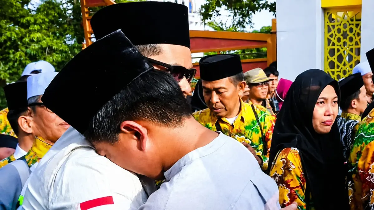 MELEPAS HARU: Putra dari salah satu tim kesehatan haji daerah memeluk orang tuanya yang bersiap naik bus saat pelepasan JCH Kloter 11 Embarkasi Banjarmasin, Kabupaten HSU. (Foto: M. Akbar) 
