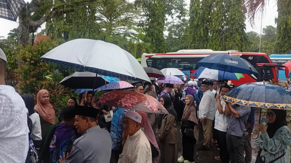 PAKAI PAYUNG:Di tengah guyuran hujan, keberangkatan Jemaah Calon Haji Kabupaten HSS menuju Asrama Haji dilepas keluarga, Sabtu (9/5/2026) pagi.(Foto:M Padil Ihsan/Radar Banjarmasin)&nbsp;
