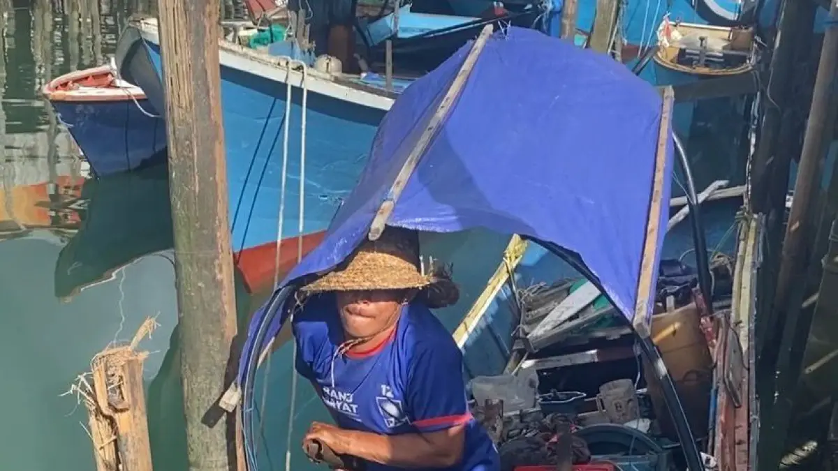 SIBUK: Salah satu nelayan di Desa Rampa, Hamdani, hanya bisa menyibukkan diri memperbaiki mesin kapalnya di dermaga. (Foto: Jumain/ Radar Banjarmasin)&nbsp;