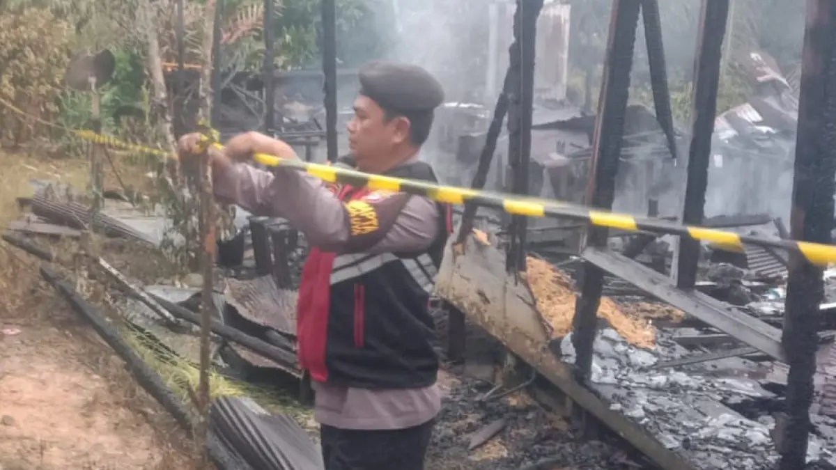 DIBATASI: Anggota Polsek Muara Uya memasang garis polisi di lokasi kebakaran di Desa Lumbang, Tabalong.&nbsp;