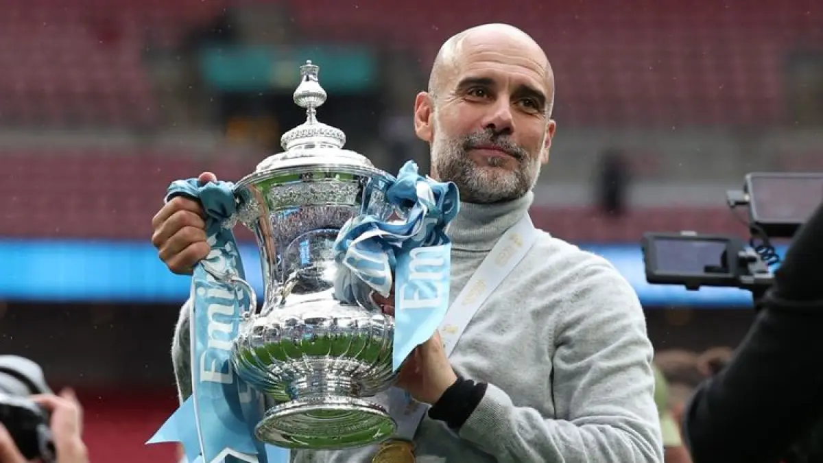 BERPOSE: Pep Guardiola berpose dengan trofi setelah pertandingan sepak bola final Piala FA antara Chelsea vs Manchester City di stadion Wembley, Sabtu (16/5).&nbsp;
(AFP/ADRIAN DENNIS