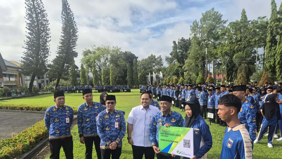 TERJAMIN: Wakil Bupati Kabupaten Tanah Laut (Tala), H Muhammad Zazuli didampingi Kepala BPJS Ketenagakerjaan Tala, Ardhinata Surya menyerahkan kartu BPJS Ketenagakerjaan kepada atlet Kabupaten Tala yang berlaga di POPDA Kalsel 2026 secara simbolis pada Apel Kerja Gabungan, Senin (18/5/2026).(Foto:BPJS Ketenagakerjaan untuk Radar Banjarmasin)
