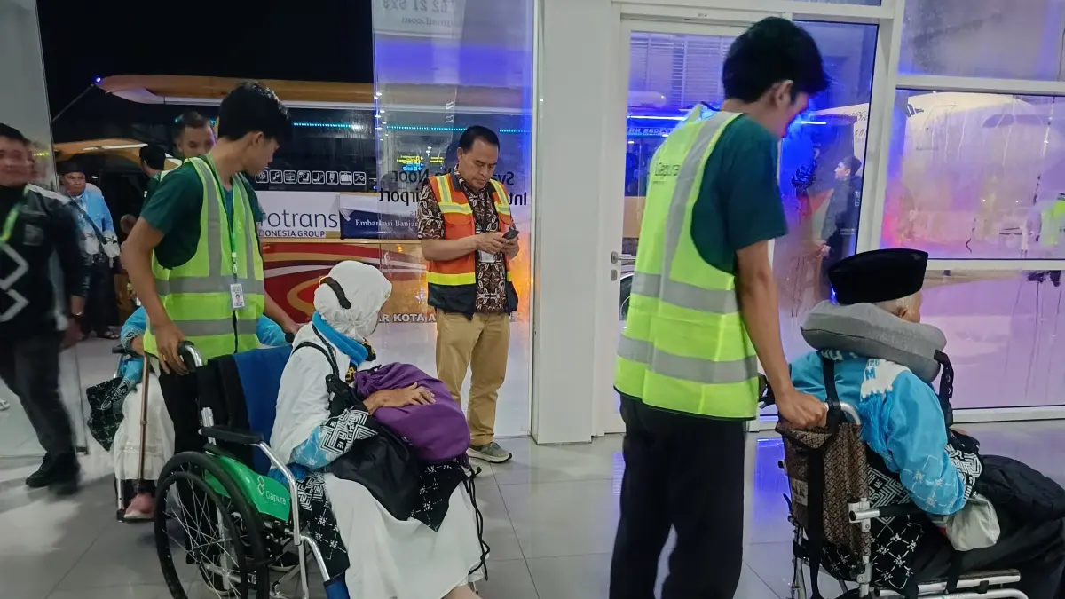 Petugas haji membantu jamaah lansia Embarkasi Banjarmasin saat persiapan keberangkatan haji. PPIH memperketat pengawasan layanan jamaah menyusul isu pungli jasa kursi roda di Tanah Suci. (SHEILLA FARAZELA/RADAR BANJARMASIN)