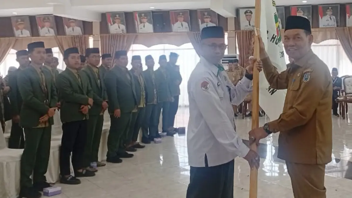 DILEPAS: Bendera diserahkan Ketua LPTQ HSS H Suriani sebagai tanda dilepasnya Kafilah HSS dengan jumlah 130 personel untuk mengikuti MTQ XXXVII Kalsel di Barito Kuala. 