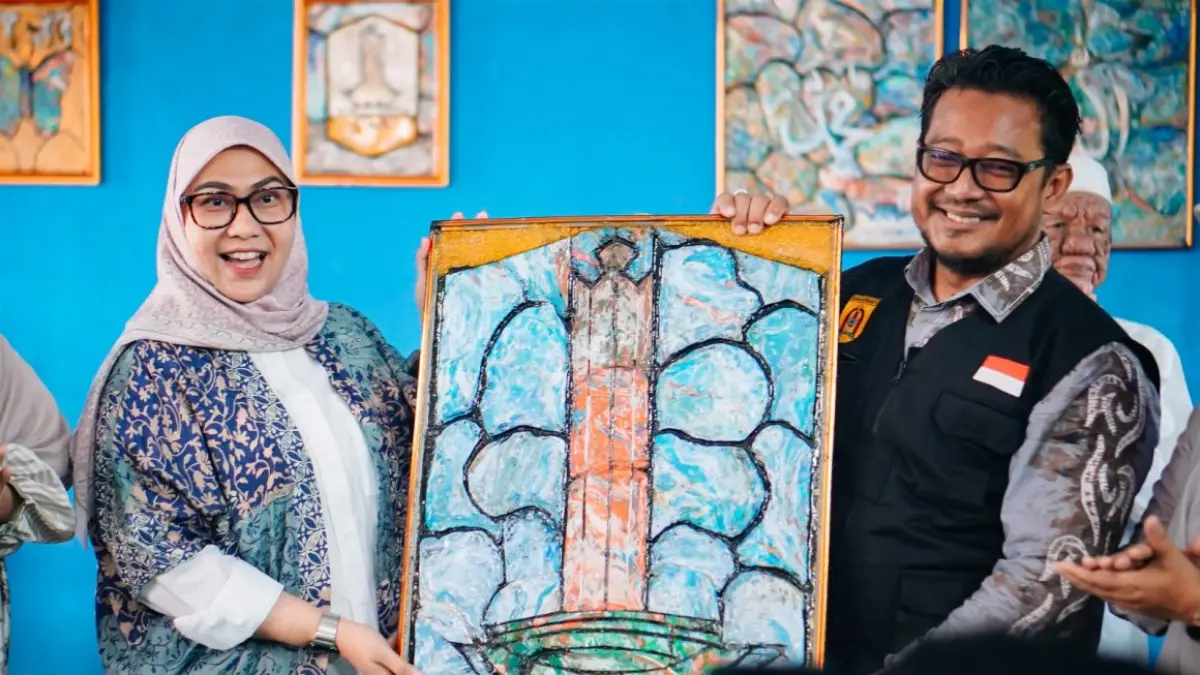 CENDERAMATA KREATIF: Wali Kota Banjarbaru, Hj Erna Lisa Halaby, menerima kenang-kenangan berupa lukisan ikonik Kota Banjarbaru dalam acara peringatan satu tahun Program MARKISSA di Gedung Serba Guna RW 007, Kelurahan Syamsudin Noor, Selasa (16/6/2026).(Foto: MC Banjarbaru)