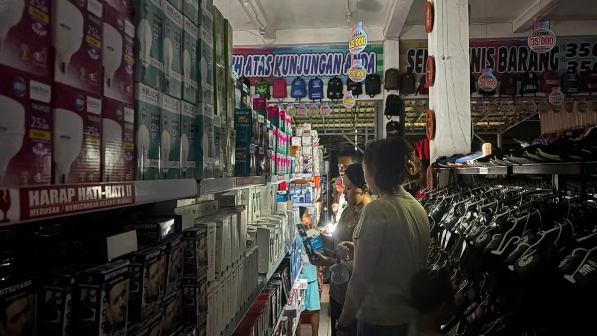 GELAP: pengunjuk salah satu toko ritel di Jalan Trans Kalimantan, Handil Bakti, Kabupaten Barito Kuala menggunakan senter pribadi untuk melihat pakaian akibat pemadaman listrik. (Zulvan Rahmatan/Radar Banjarmasin)