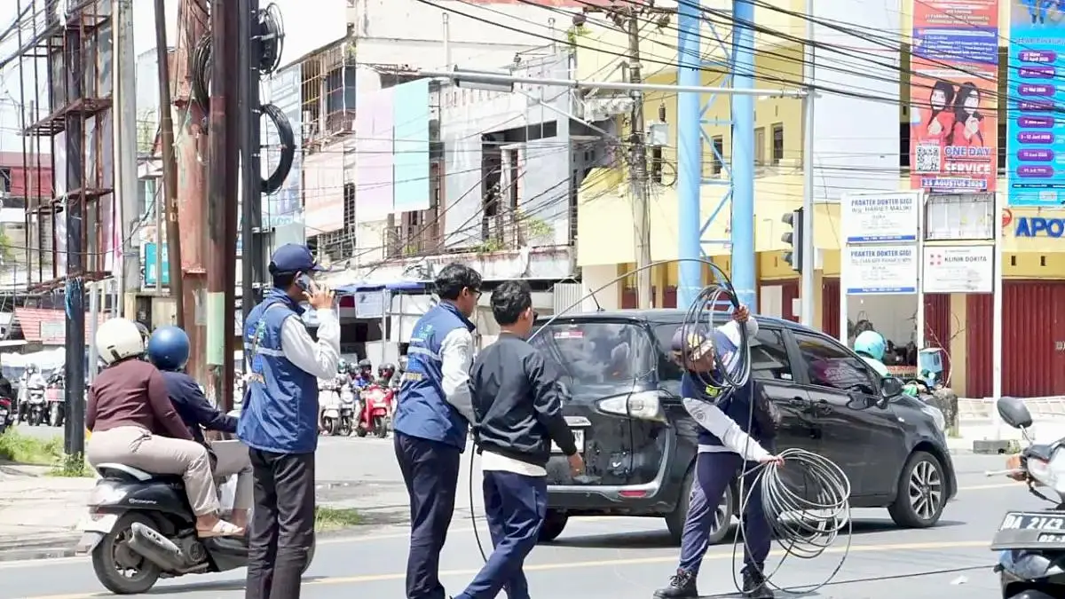 KABEL: Petugas Dinas Perhubungan (Dishub) Kota Banjarmasin membenahi kabel yang menjuntai dan mengganggu pengguna jalan. (Foto: Endang Syarifuddin/Radar Banjarmasin)