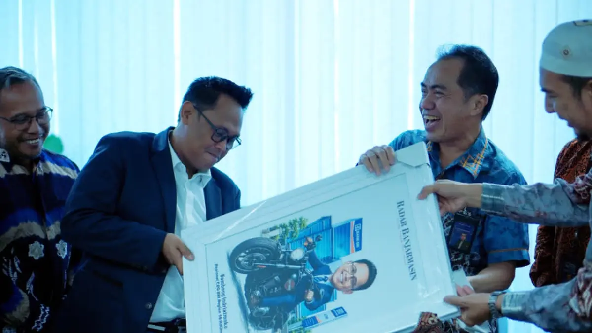 KARIKATUR: Direktur Utama Radar Banjarmasin, H Suriansyah Achmad menyerahkan karikatur ke RCEO BRI Region 14, Bambang Indriatmoko, Kamis (9/7/2026).(Foto: Raudah Anisya/Radar Banjarmasin)