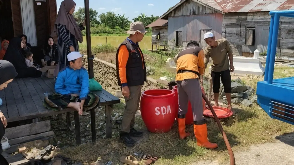 DARURAT: Petugas BPBD Kabupaten Banjar mengisi tandon air bersih untuk kebutuhan memandikan jenazah warga di Desa Sungai Rangas, Kecamatan Martapura Barat, setelah air sungai tak lagi layak digunakan akibat pencemaran bangkai ikan. (FADLAN ZAKIRI/RADAR BANJARMASIN)
