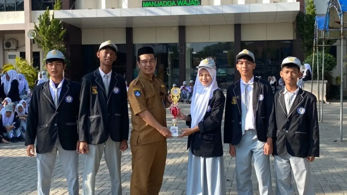 PRESTASI: Kepala SMK Negeri 3 Banjarmasin menyerahkan piala kepada Tim Sapakawanan Project yang meraih Juara I Lomba Video Kreatif Literasi Asuransi tingkat nasional. (Foto: SMK Negeri 3 Banjarmasin)
