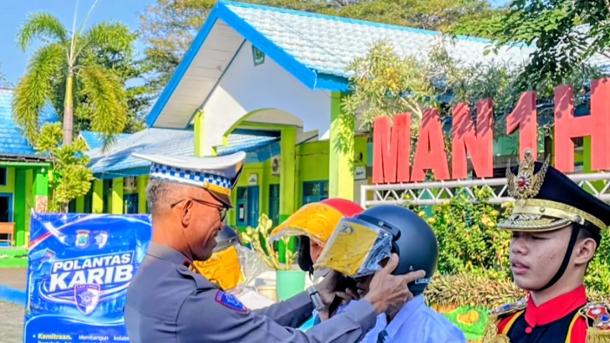 EDUKASI: Kasat Lantas Polres HSU, Iptu Tri Widodo Setiawan memberikan helm keselamatan berlalu lintas kepada siswa MAN 1 Amuntai pada Police Go To School, Senin (3/8/2026).