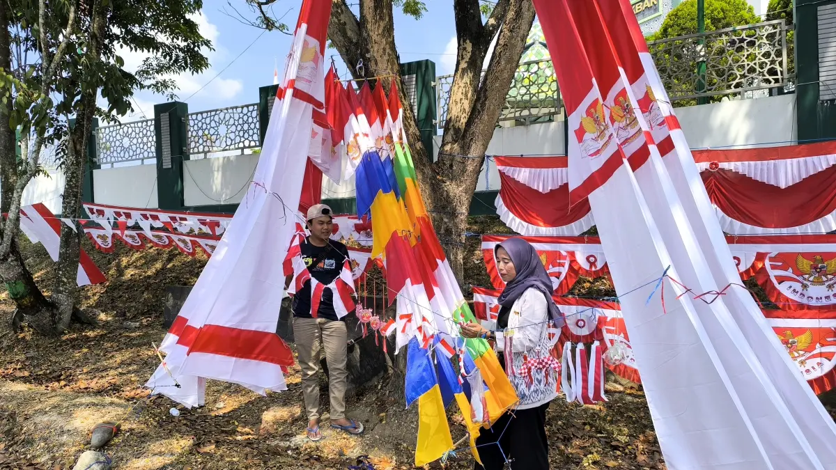 KEMERDEKAAN: Faisal, salah satu pedagang musiman asal Jawa Barat saat memajang atribut dan pernak-pernik merah putih dagangannya di pinggir Jalan A Yani, Paringin Selatan. (M Dirga/ Radar Banjarmasin)