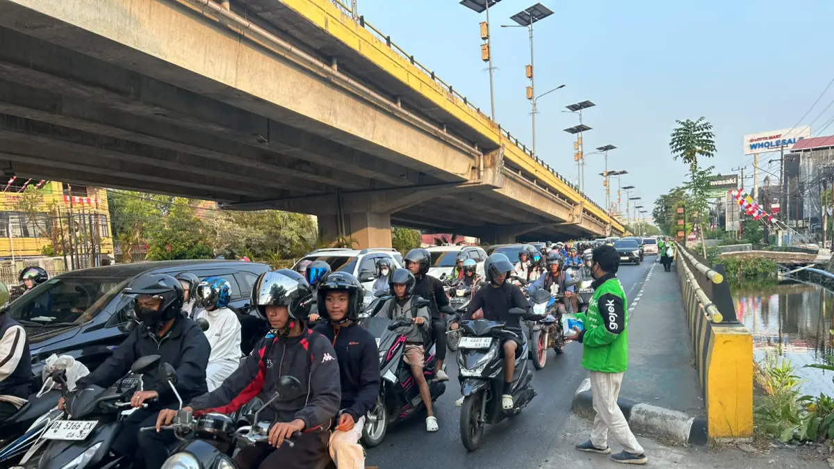 Pengemudi ojol membagikan masker gratis kepada pengguna jalan di kawasan bawah Jembatan Fly Over Banjarmasin.  (Foto: komunitas ojol untuk radar Banjarmasin)