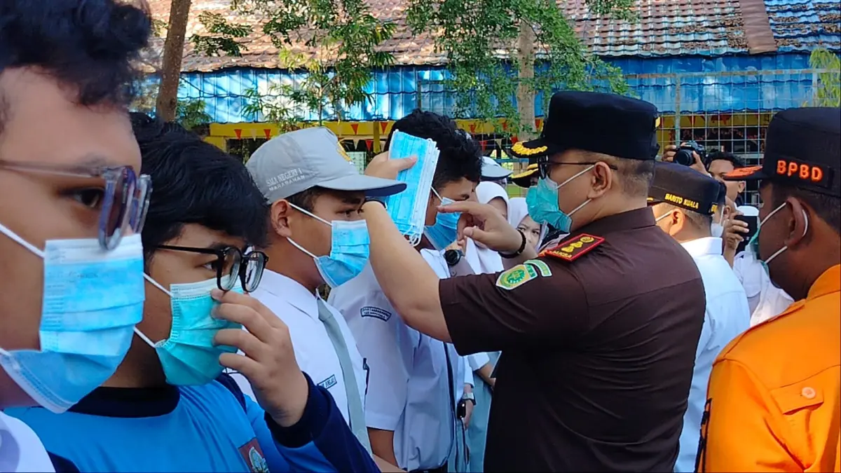 KENAKAN MASKER: Kajari Barito Kuala Andrianto Budi Santoso mengenakan masker kepada pelajar SMAN 1 Marabahan.//Maulana