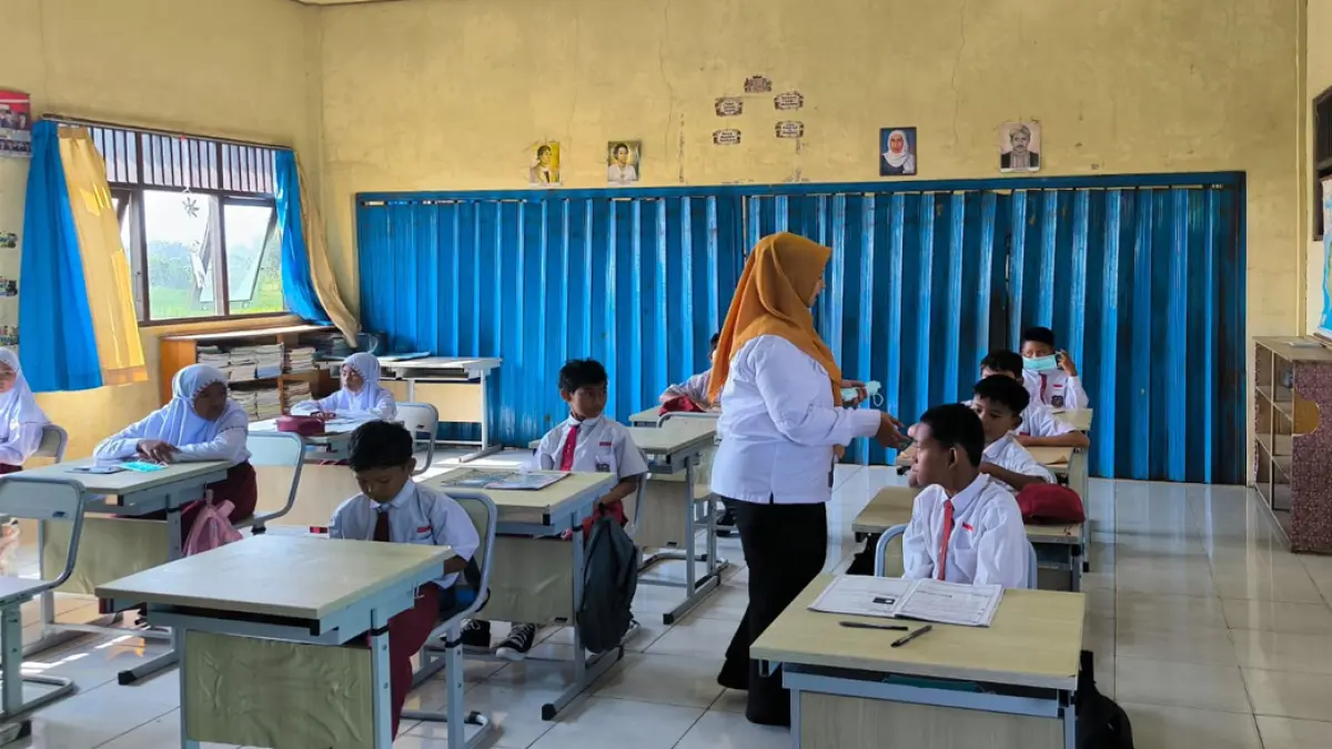 PENYESUAIAN: Kepala Disdikbud Tala Myrza Fazrina saat membagikan masker ke siswa SDN 2 Pandahan yang terdampak kabut asap karhutla.