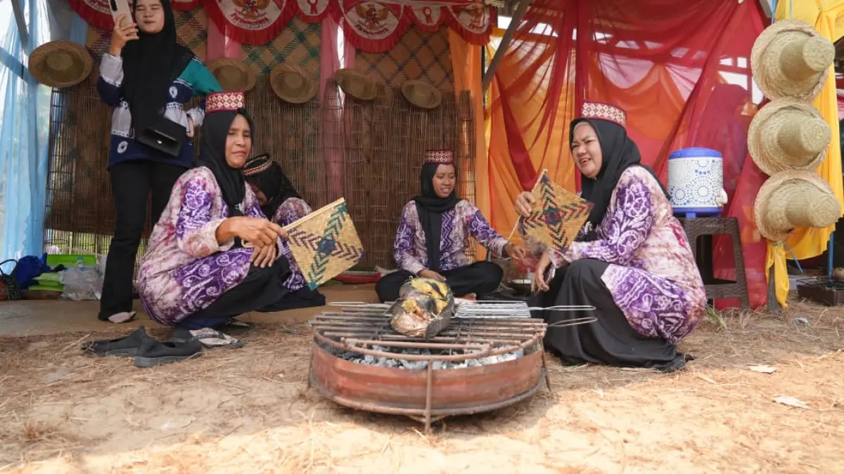 NIKMAT: Ibu-ibu dari Desa Jambu Baru, Kecamatan Kuripan saat memanggang ikan haruan.(Foto-foto: YABN)
