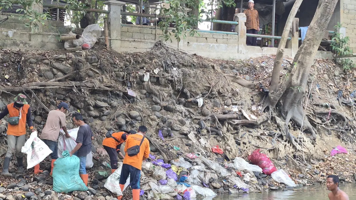 BERSIH-BERSIH: Pasukan Kuning DLH HST membersihkan bantaran Sungai Barabai dari tumpukan sampah. (Foto: Jamaluddin/Radar Banjarmasin).