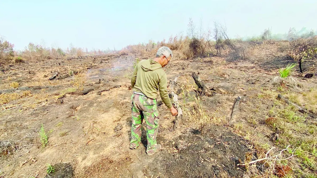 TERBAKAR: Bambang, guru SDN 2 Landasan Ulin Utara saat berada di kebunnya yang hangus terbakar.&nbsp;
(Foto: SHEILLA FARAZELA/RADAR BANJARMASIN)