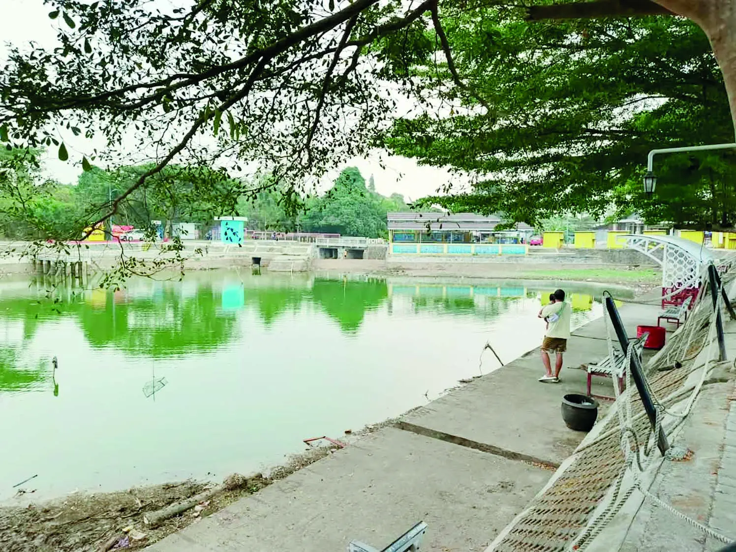 SORE: Seorang pengunjung menggendong anak di bawah pohon di tepi Embung Sidodadi. (Foto: Sheilla Farazela)