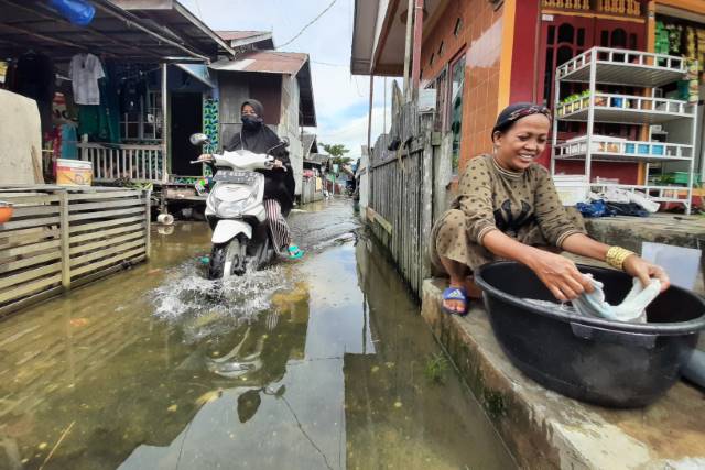 TETAP TERSENYUM: Genangan di Jalan Prona, Banjarmasin Selatan. Ini salah satu kawasan yang terdampak paling parah selama banjir rob pada Desember kemarin. | FOTO: WAHYU RAMADHAN/RADAR BANJARMASIN