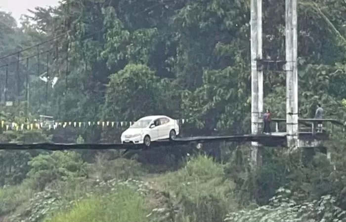 Seorang wanita dan mobil Sedannya yang terjebak di jembatan gantung kecil di atas Sungai Yom, Thailand./The Pattaya News